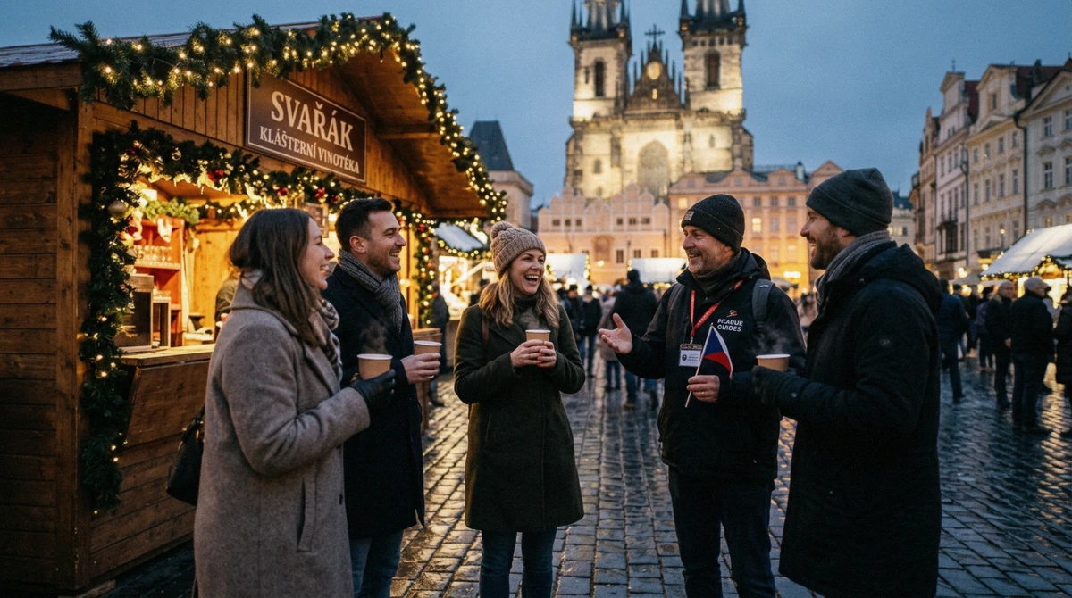 A small group with paper cups of mulled wine around a guide beside a lit market hut in Prague at dusk