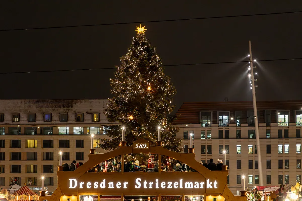 The lit arch at the entrance to the Striezelmarkt on Dresden's Altmarkt with the market tree behind it