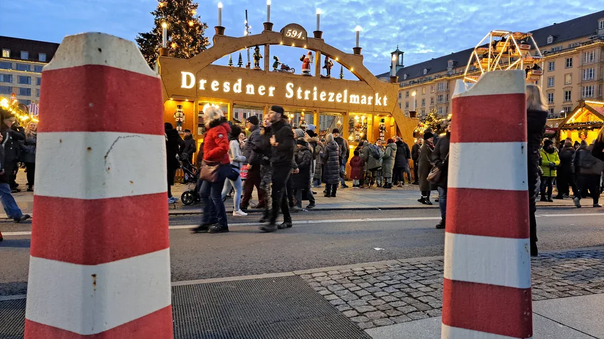 Crowds walking under the lit Dresdner Striezelmarkt entrance arch at the Dresden Christmas market