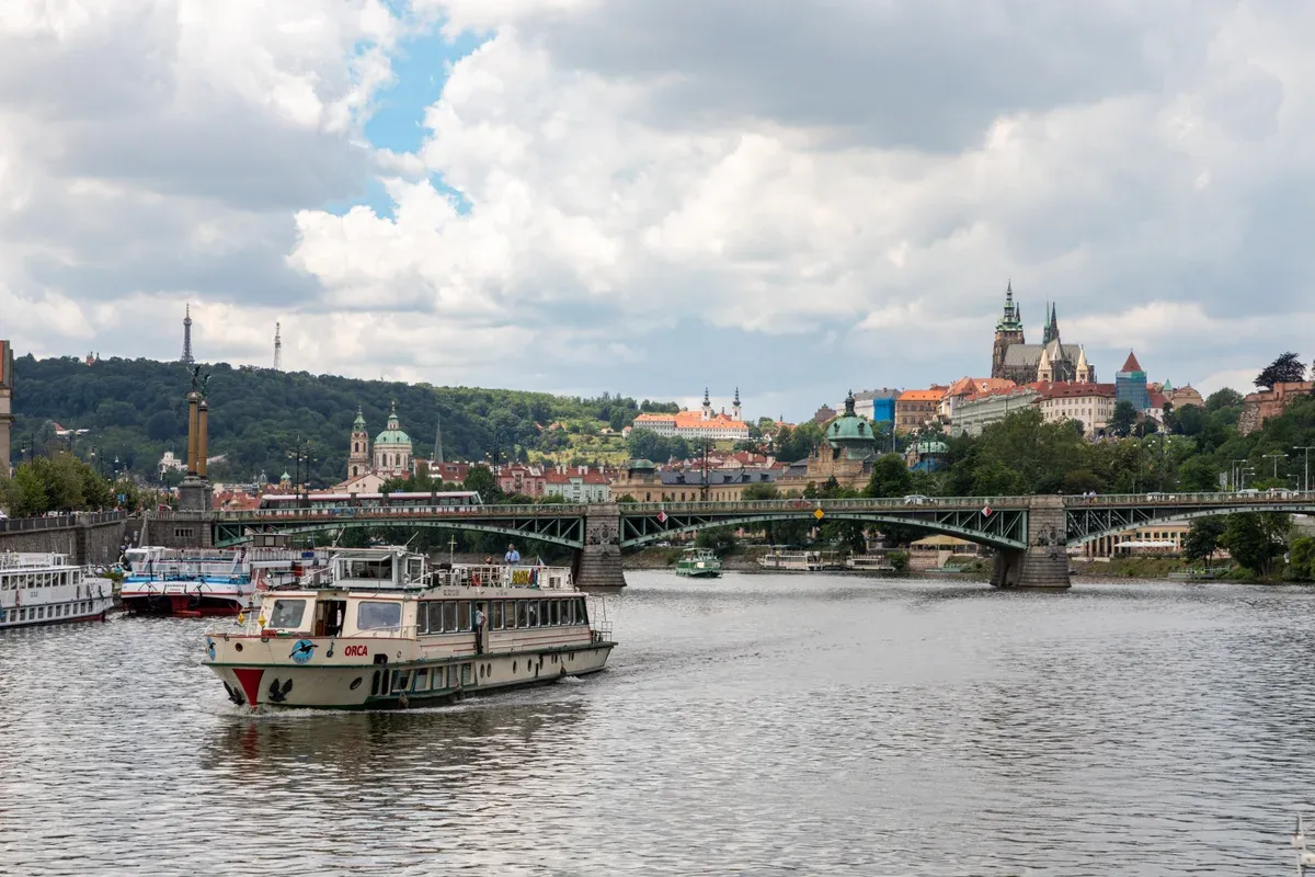 Vltava cruise boat passing under the bridges with Prague Castle on the skyline
