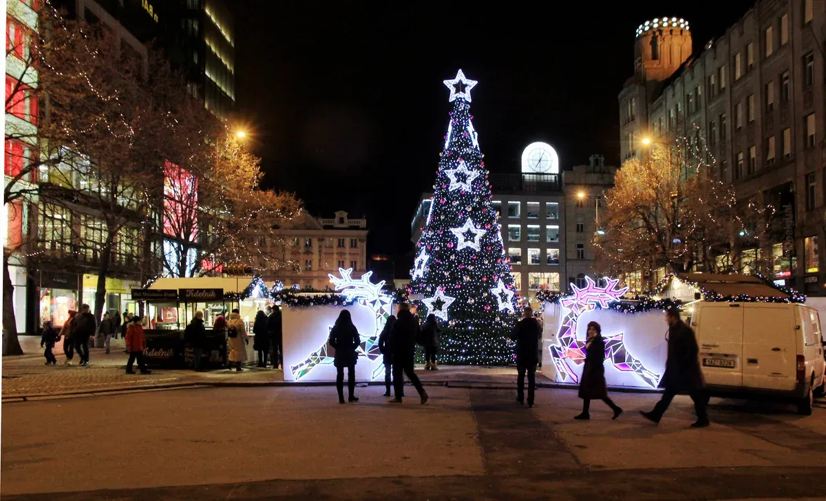 Market stalls and a lit Christmas tree at the lower end of Wenceslas Square at night